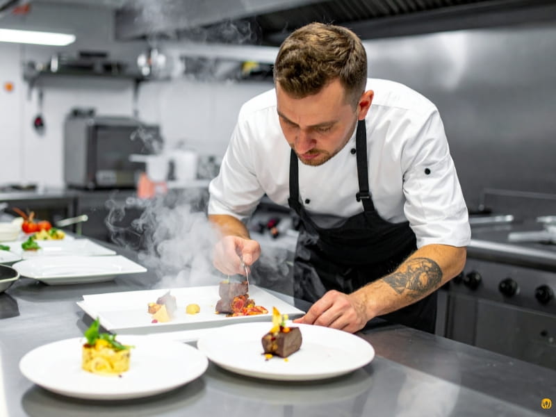 Szef kuchni układa danie na talerzu w nowoczesnej kuchni – demo strony gastronomicznej