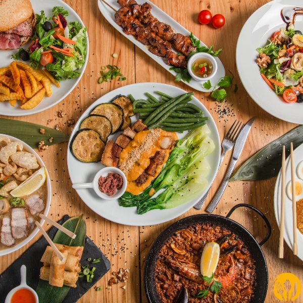 Stół z różnorodnymi daniami: grillowane mięsa, sałatki i dodatki; ujęcie z góry.