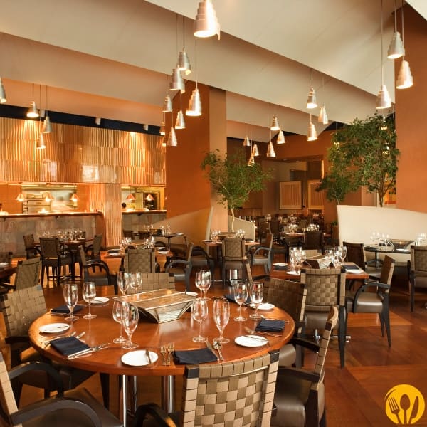 Wnętrze restauracji z okrągłymi stolikami i ciepłym oświetleniem